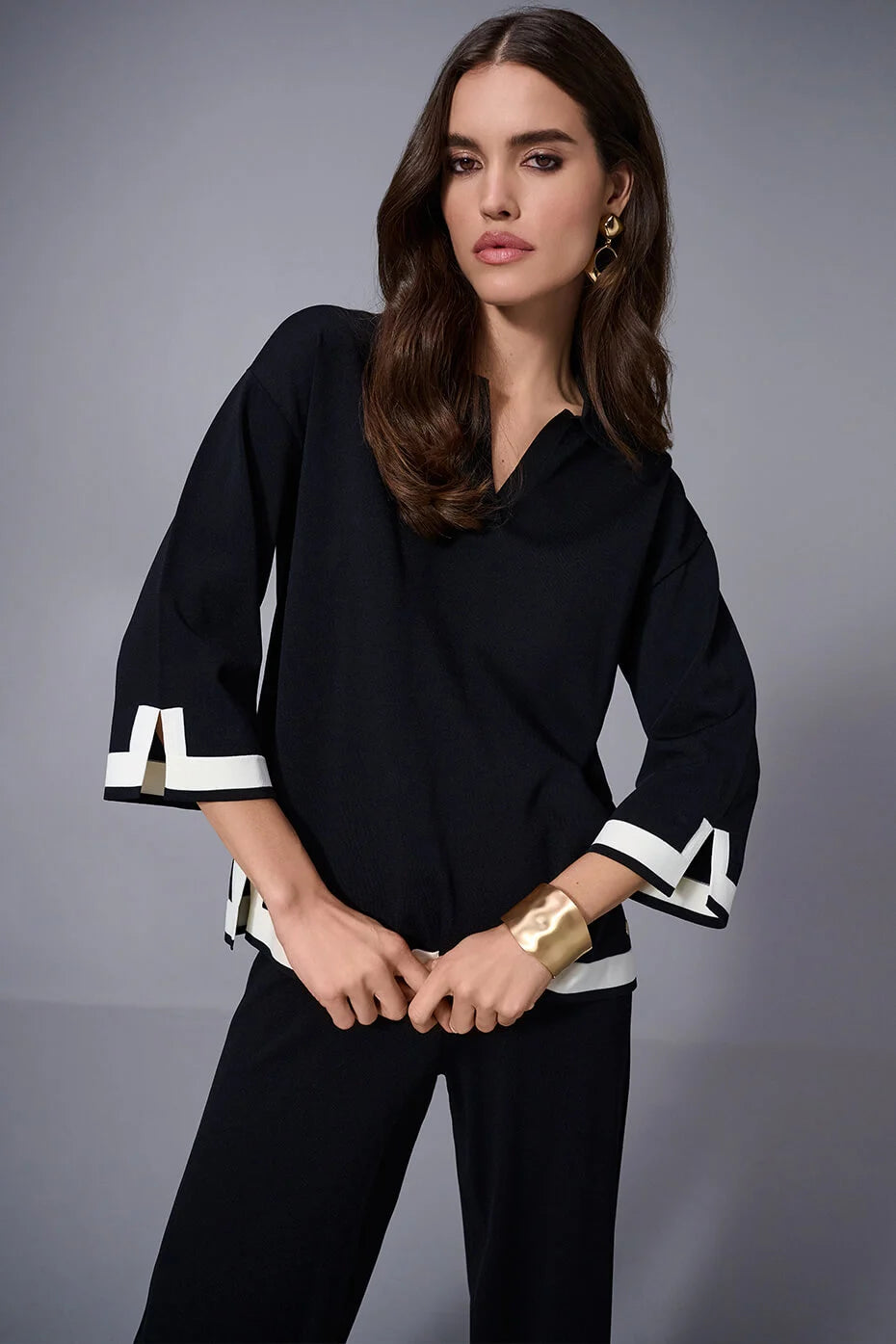 Woman wearing a black outfit with white accents on a gray background