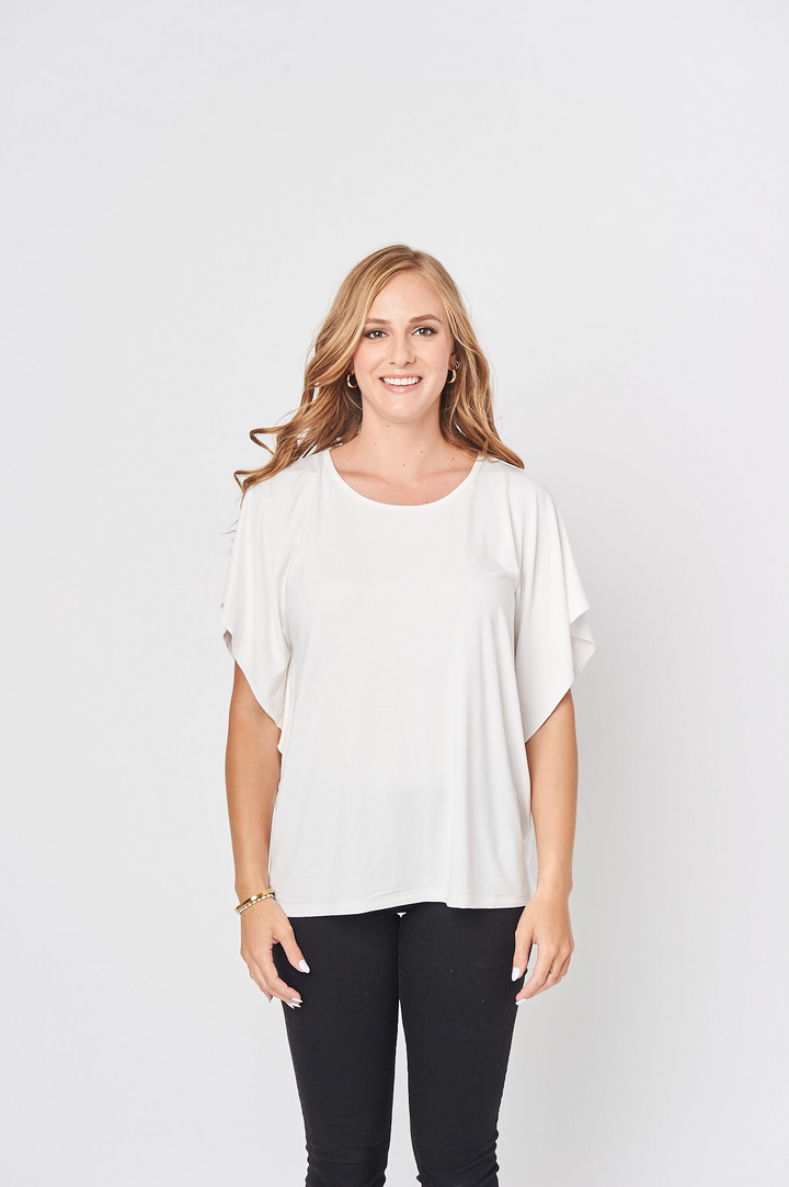A woman wearing an off white, short sleeve, round neckline top with butterfly sleeves and a relaxed fit.