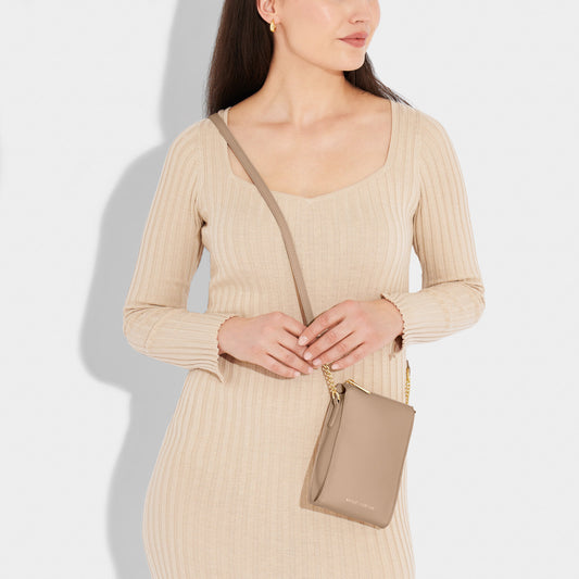 A model is wearing the The Zana Slim Crossbody in Soft Tan color.