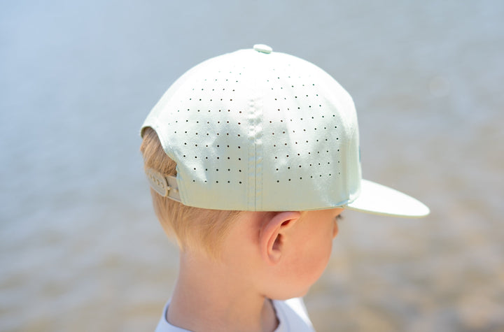 Child wearing a white cap with a blurred natural background