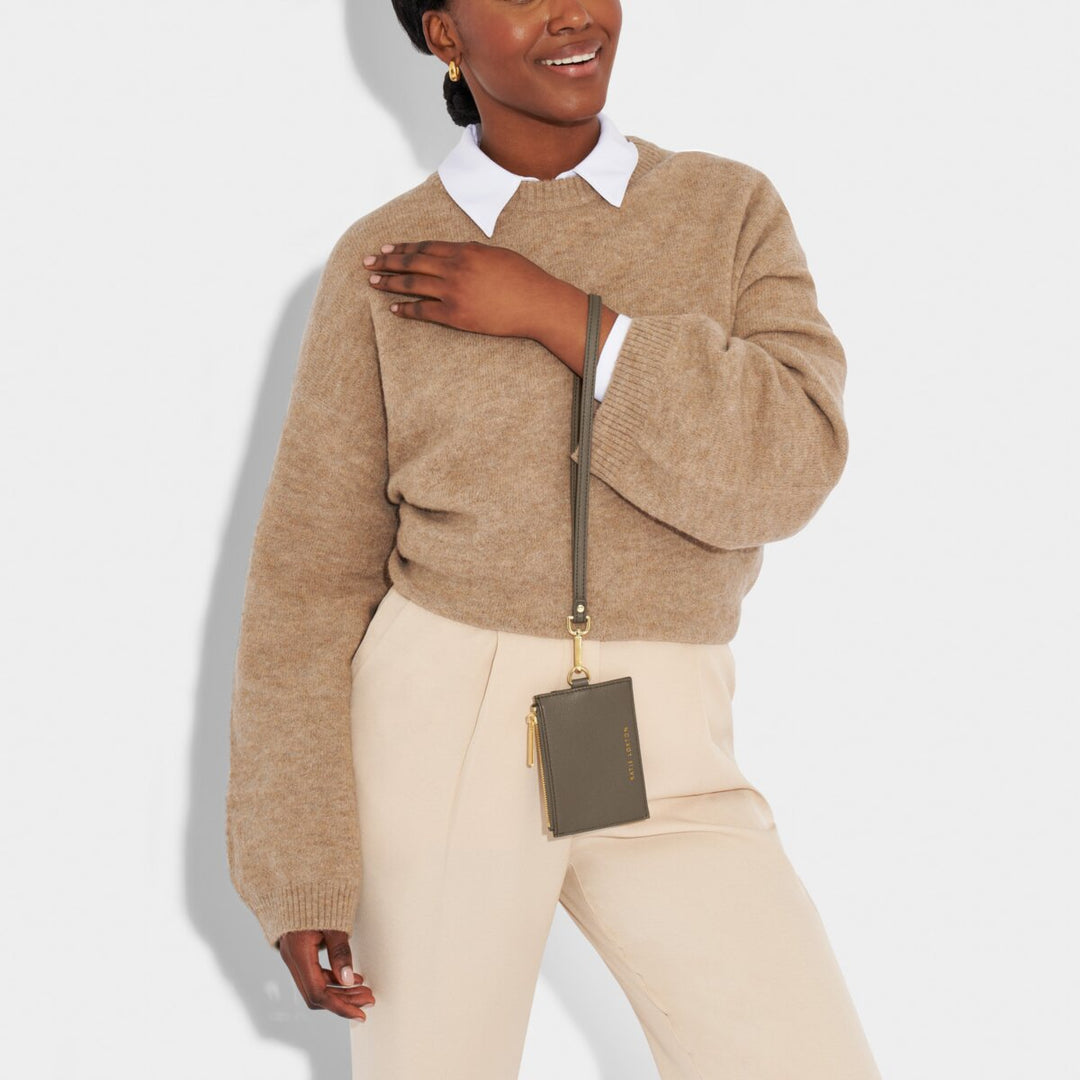 The model in the picture is holding the Ashley Cardholder with Strap in Mink color by its strap.