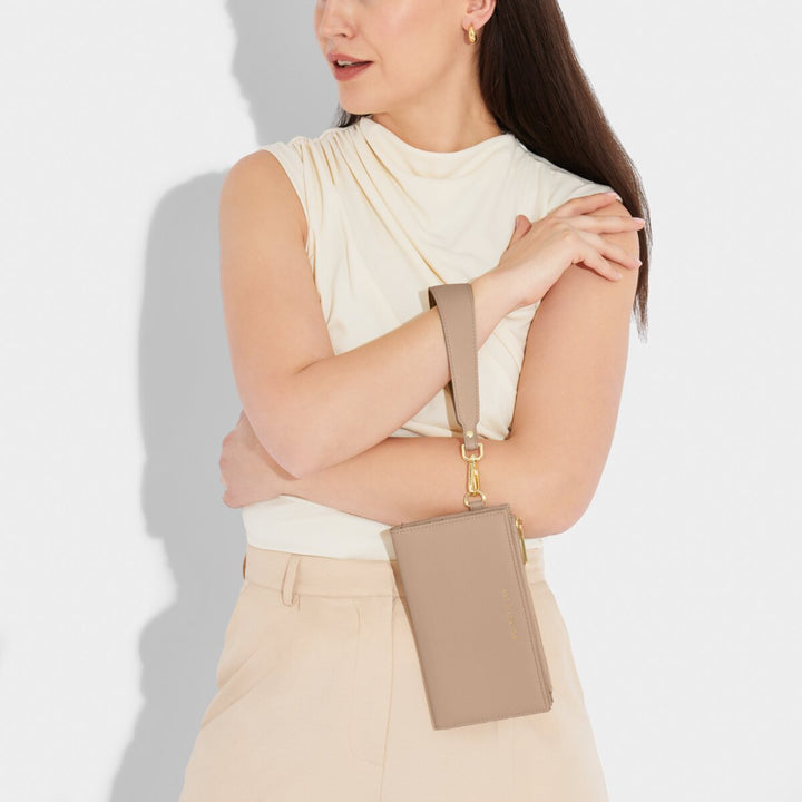A model holding the Zana Fold Out Wristlet Wallet - Soft Tan color.