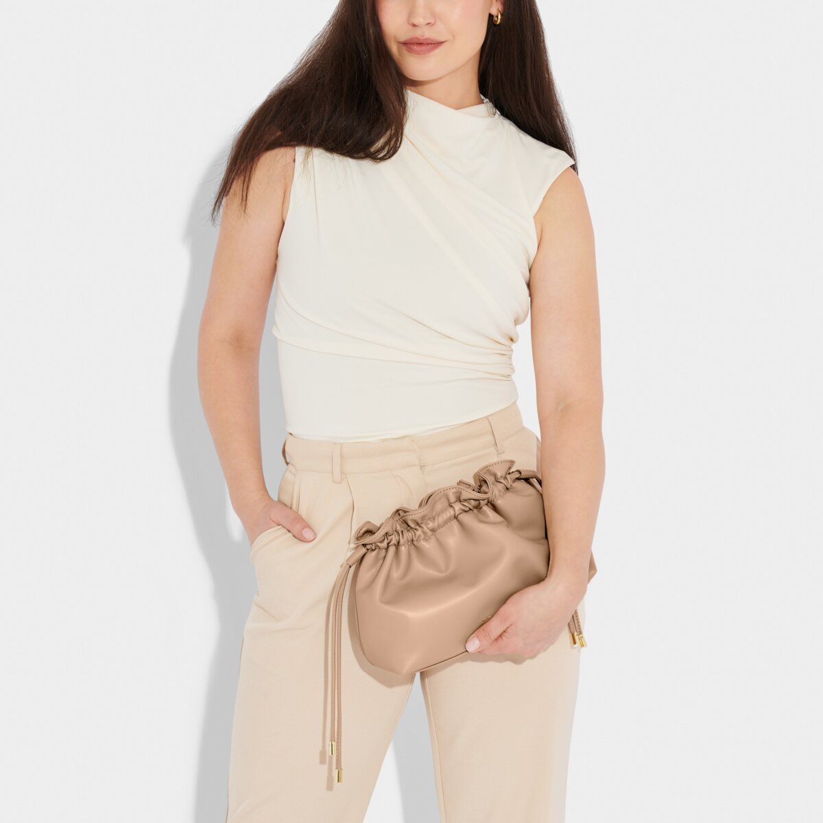 A model holding the Hailey Crossbody Clutch in Soft Tan.