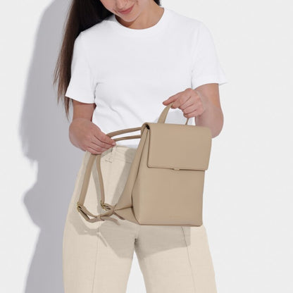 A lady holding the Demi Backpack in light taupe color.