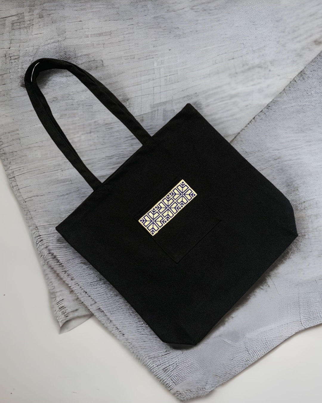 Tatreez Fabric Tote Bag in Black color and Blue embroidery on the outside pocket.